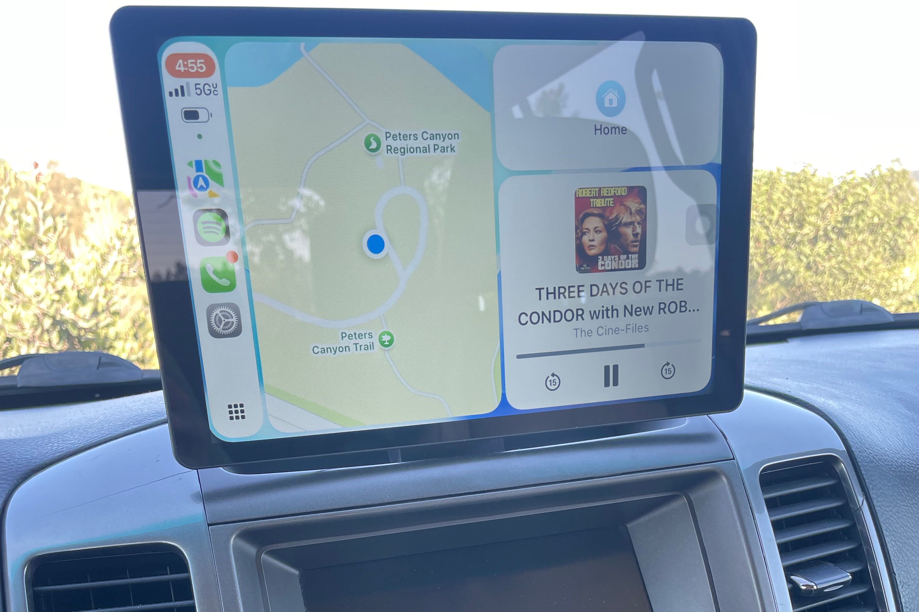 Carplay screen mounted in vehicle displaying a map and audio file playing