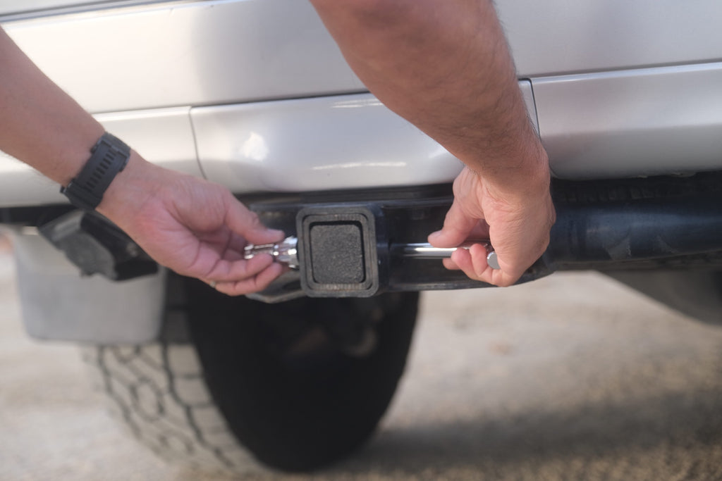 Image showing hitch stash in the closed position. Displayed with a combination lock hitch pin that is being removed. The lock hitch pin is not included.